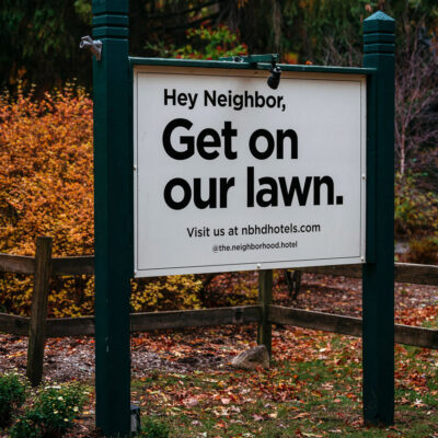 An entrance sign that says "Hey Neighbor, Get on our Lawn" at The Neighborhood Hotel in New Buffalo, Michigan.