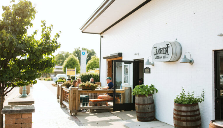 The white brick facade and outdoor seating area of Transient Artisan Ales in Bridgman, Michigan.