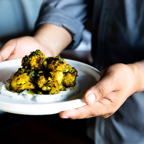 A chef holding plated charred cauliflower at Bentwood Tavern in New Buffalo, Michigan.