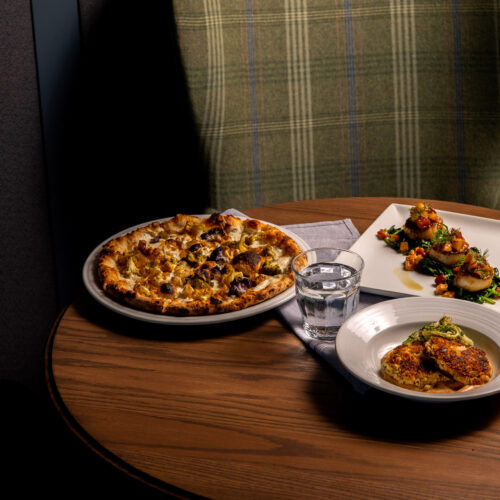 A pizza and various small plates on a table at Bentwood Tavern in New Buffalo, Michigan.