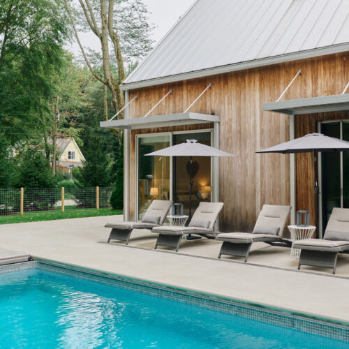 A sprawling veranda with lounge chairs and pool set against nature and the home’s contemporary architecture at Sol Haus in Union Pier, Michigan.