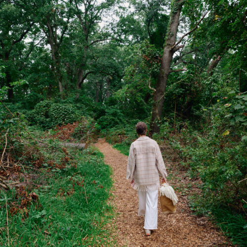 A woman carries a picnic basket along a forest path at Sol Haus in Union Pier, Michigan.
