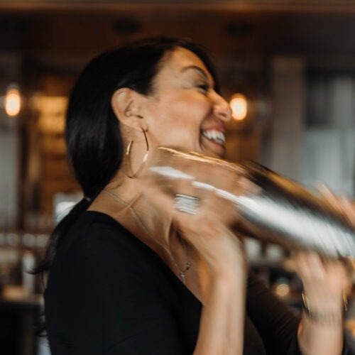 A bartender laughing while shaking a cocktail at Terrace Room in New Buffalo, Michigan.