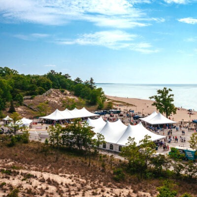 Aerial view of the tents, crowds, and lakefront location of Maker’s Trail Festival in Bridgman, Michigan.