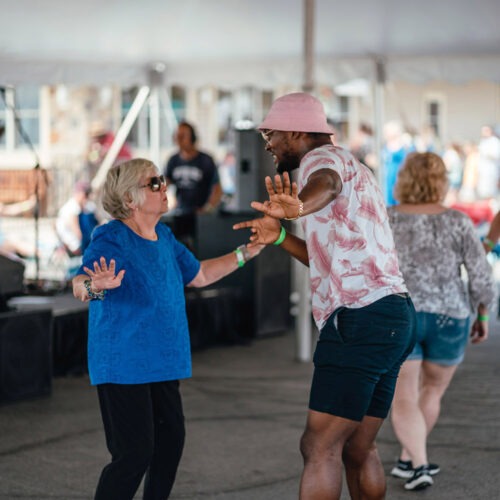 An older woman and younger man playfully dancing together at Maker’s Trail Festival in Bridgman, Michigan.