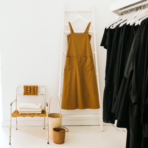 Butterscotch cotton sundress hung from a white ladder styled with a vintage chair and baskets of the same colors at AP Shops in Lakeside, Michigan.