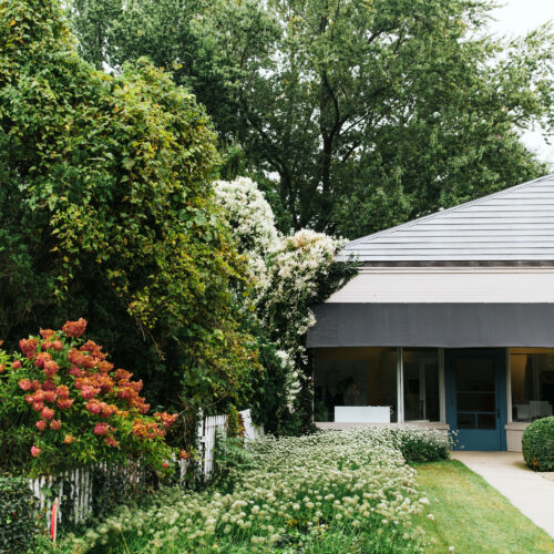 An exterior view of the shop amongst trees and flowers at AP in Lakeside, Michigan.