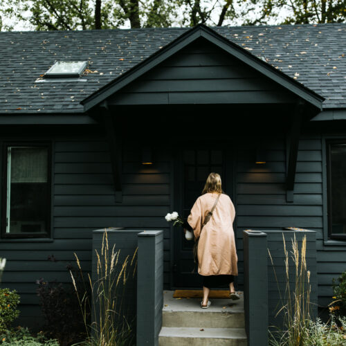 Owner, Ariane Prewitt, enters through the front door with fresh flowers of the cottage at Shamrock House in Harbert, Michigan.