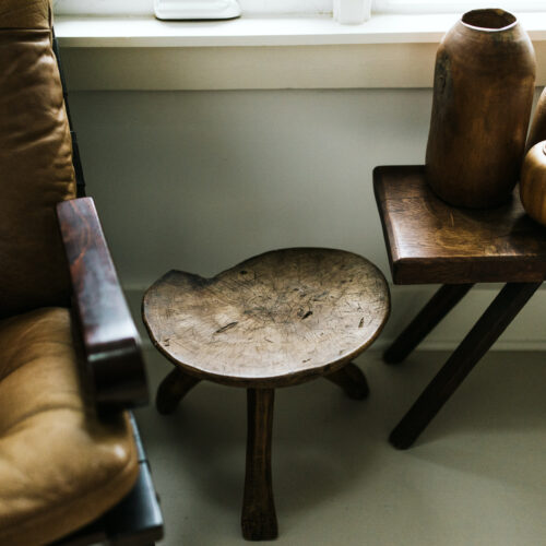 A detail shot of a dark leather chair and wood stool at Shamrock House in Harbert, Michigan.