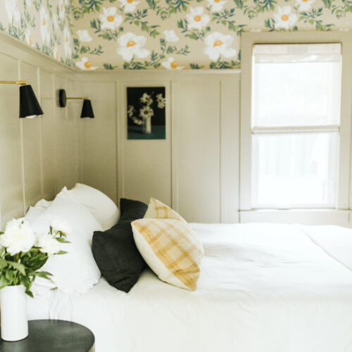 A cozy bedroom with taupe paneling and floral wallpaper at Shamrock House in Harbert, Michigan.