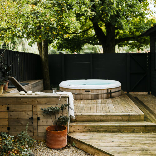 A wood patio with a built-in hot tub under a canopy of trees at Shamrock House in Harbert, Michigan.