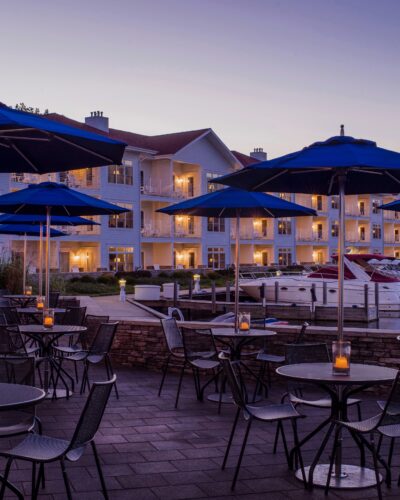 Candlelight tables with blue umbrellas overlook boats in the marina at Bentwood Tavern in New Buffalo, Michigan.