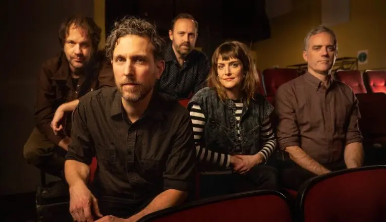 Members of the band Great Lakes Swimmers turn to face the camera from theater seats.