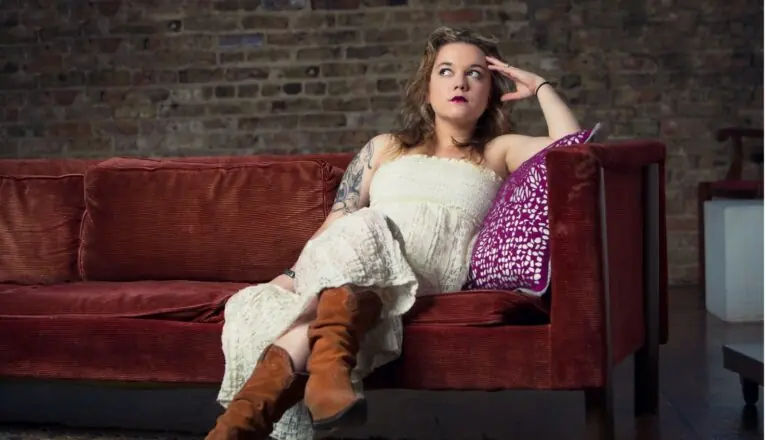 Musician Lydia Loveless sitting on a rust-colored sofa.