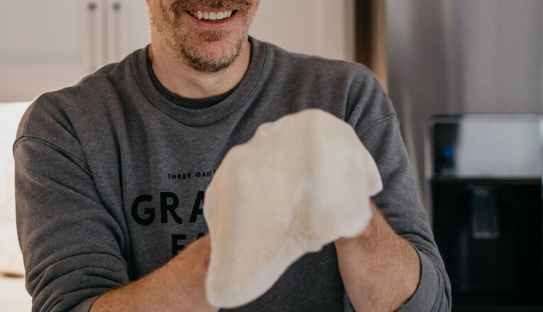 A man smiling tossing pizza dough at Granor Farm in Three Oaks, Michigan.