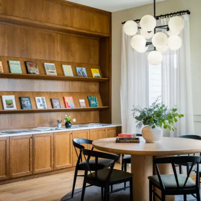 A corner of the Living Room with a round table and chairs and a curated wall of reading materials at Marina Grand Resort in New Buffalo, Michigan.