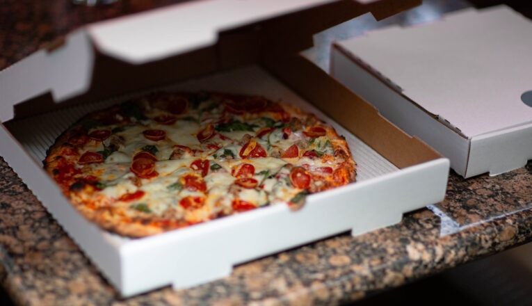 A pizza box half opened giving a peek of a deluxe pizza inside at Brewster's in New Buffalo, Michigan.