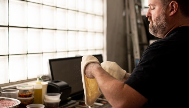 Co-owner Pat Mullins hand-shaping pizza dough in the kitchen at Patellies in Three Oaks, Michigan.