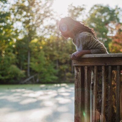 A woman looking out on a lake from a wooden overlook platform.