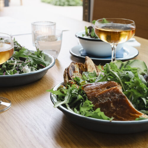 A fresh green salad wit smoked salmon and roasted potatoes with a glass of sparkling skin contact wine.