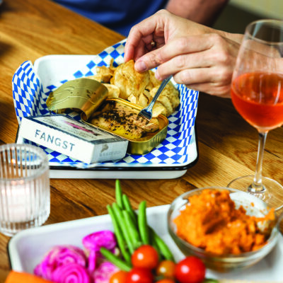 A hand reaches for fresh vegetables over a spread of colorful dishes.
