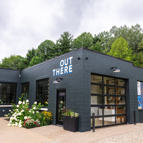 The black brick exterior of Out There with branded artwork painted on the side of the building.