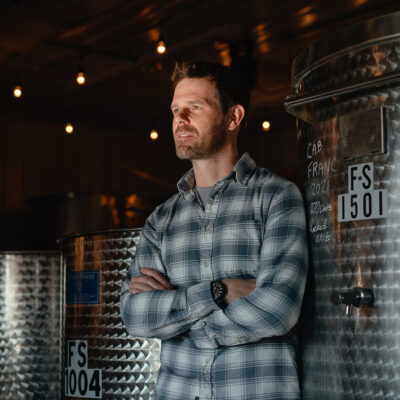 Owner and winemaker Adam McBride standing in front of metal wine barrels at Hickory Creek Winery in Buchanan, Michigan.