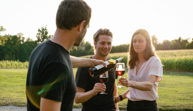 Owner and winemaker Adam McBride pouring a glass of wine for guests outside at Hickory Creek Winery in Buchanan, Michigan.