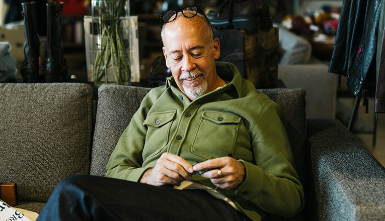 A man in a green sweater knits in Good and Heroes in Three Oaks, Michigan