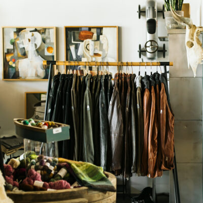 Framed artwork is displayed behind a rack of leather jackets inside Goods and Heroes in Three Oaks, Michigan