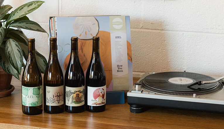 Four bottles of wine next to records and a record player at Out There located in Sawyer, Michigan