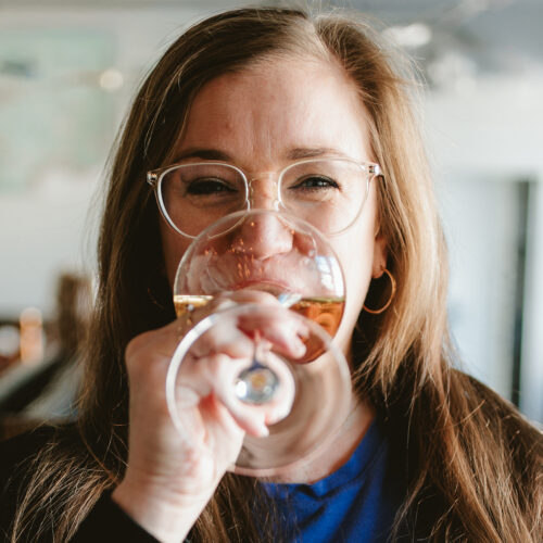 Ellie Mullins smiling and drinking wine at P&E Bottle Shop in Three Oaks, Michigan