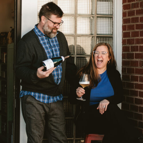 Ellie and Pat Mullins laughing and drinking wine at P&E Bottle Shop in Three Oaks, Michigan