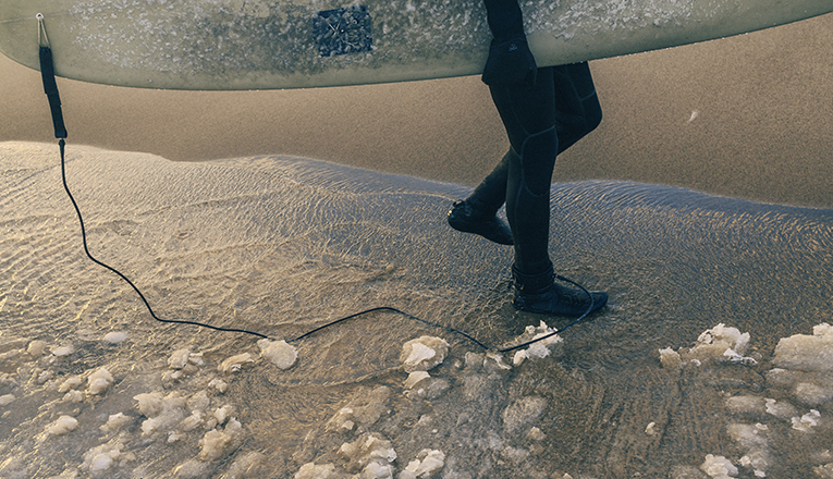 A surfer walks through ice in Lake Michigan