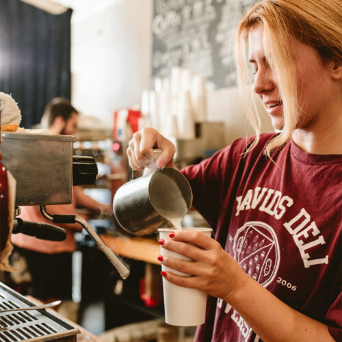 A barista wears a David's Deli University shirt while making a latte at David's Deli in New Buffalo, Michigan