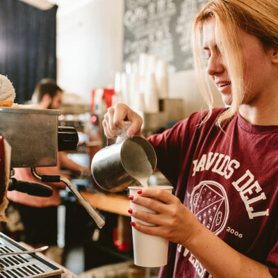 A barista wears a David's Deli University shirt while making a latte at David's Deli in New Buffalo, Michigan