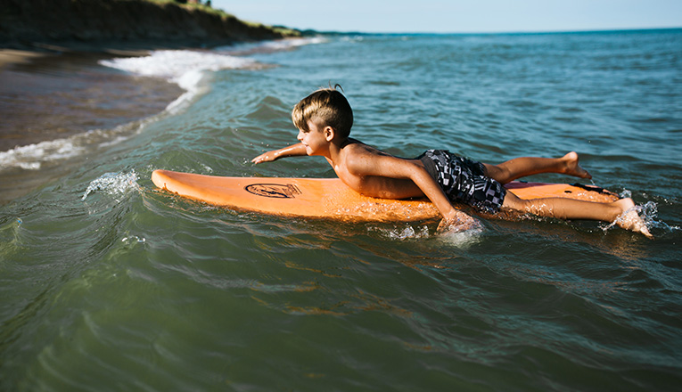 A boy paddling into a wave near New Buffalo Michigan