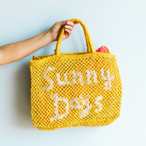 Sunny Days straw tote bag held up at BEACH in New Buffalo, Michigan