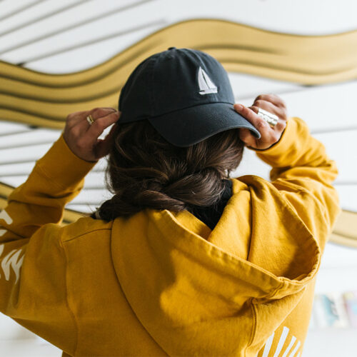 A woman puts on a sailboat hat and graphic sweatshirt at Eastern Standard Time in New Buffalo, Michigan