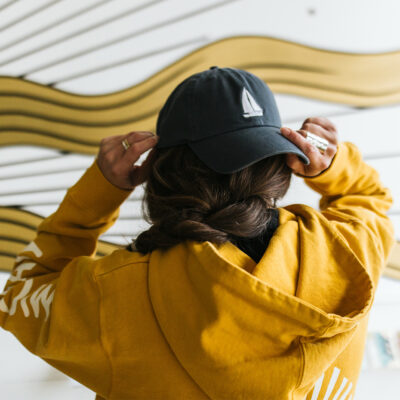 A woman puts on a sailboat hat and graphic sweatshirt at Eastern Standard Time in New Buffalo, Michigan