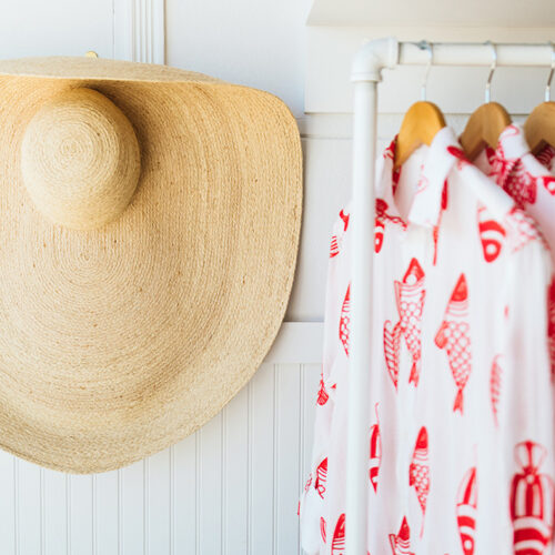 A large straw beach hat hangs on the wall next to a red and white fish shirt at Lake Feste in New Buffalo, Michigan