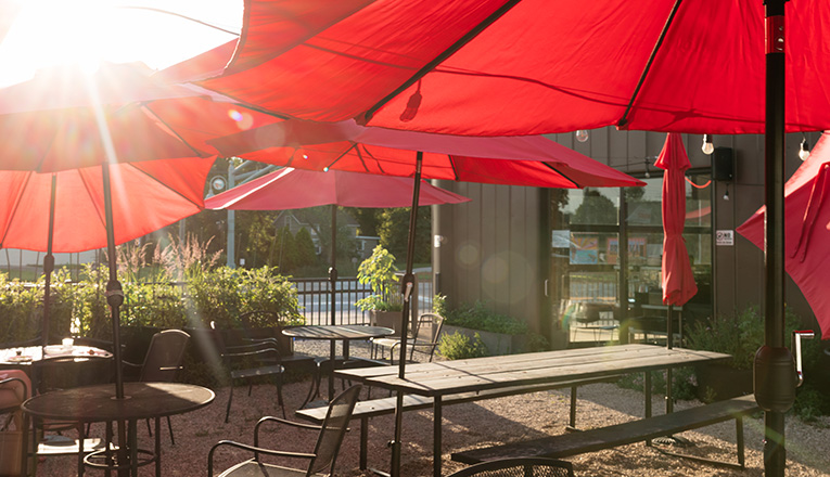 Red umbrellas shade the outdoor patio at Emma Hearth and Market in Bridgeman, Michigan