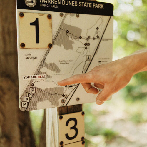 A finger points to a trail map of the Mt. Randall Loop at Warren Dunes State Park in Sawyer, Michigan