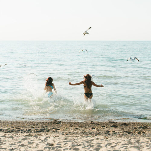 Two friends run into Lake Michigan at Warren Dunes State Park in Sawyer, Michigan