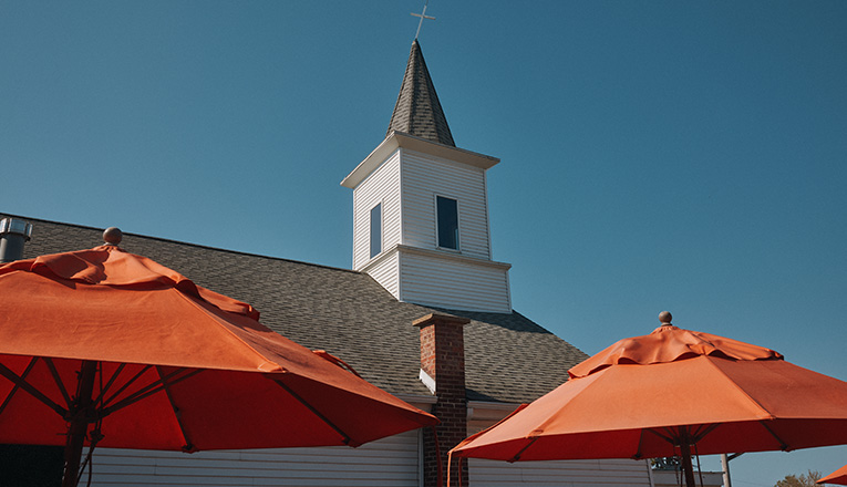 The steeple behind umbrellas on the rooftop of Beer Church in New Buffalo, Michigan